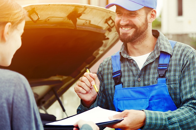 Mechanic handing paperwork to woman